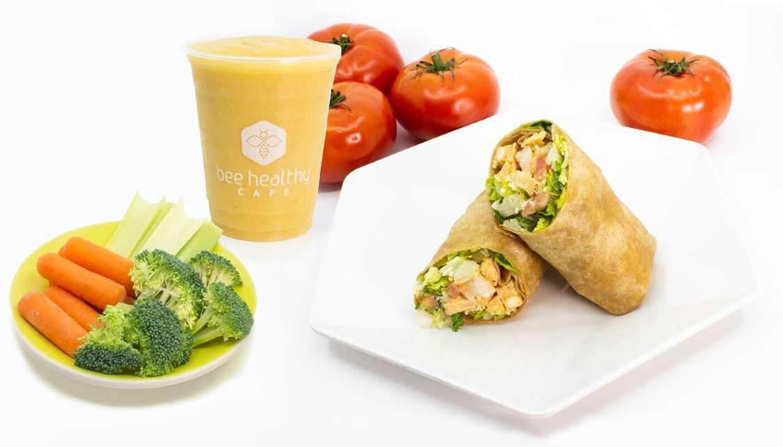 A healthy meal with a wrap, veggies, and a fruit smoothie